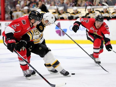 The Bruins' Patrice Bergeron tries to hold off the Senators' Dion Phaneuf with Cody Ceci closing in during the second period.