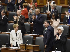 Ontario Finance Minister Charles Sousa, right, and Premier Kathleen Wynne get a standing ovation as they enter the room to deliver the 2017 Ontario budget at Queen's Park in Toronto on Thursday, April 27, 2017.