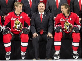 Pierre Dorion smiles as he sits between Kyle Turris, left, and Erik Karlsson for the Senators' official team picture in mid-March. He had even more reason to smile after the team clinched a playoff berth with Thursday's win in Boston.  Wayne Cuddington/Postmedia
