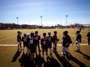 Lacrosse players stand on the sidelines of Minto Field.