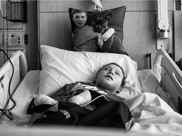 Jonathan Pitre rests in bed, his pillow with his Boston terrier, Gibson, on it close by.