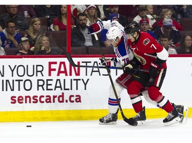 The New York Rangers' Brady Skjei and the Ottawa Senators' Kyle Turris battle for the puck.
