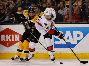 Erik Karlsson #65 of the Ottawa Senators looks to pass by Dominic Moore #28 of the Boston Bruins in the first period against the Boston Bruins in Game Three of the Eastern Conference First Round during the 2017 NHL Stanley Cup Playoffs at TD Garden on April 17, 2017 in Boston, Massachusetts.