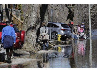 People walk along the flooded sidewalk of Belmont Avenue.