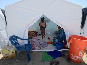 A displaced woman from a nearby community affected by the floods sweeps her family's tent at a refugee camp on the outskirts of the northern Peruvian city of Piura, on April, 5, 2017. The "El Niño" weather phenomenon caused heavy seasonal rains since the beginning of the year, leading to overflowing rivers, flash floods and mudslides in most of the northern coastal region of Peru. It's an example of, writes Eva Schacherl, problems caused by climate change.  /