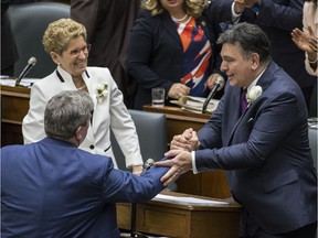 Ontario Finance Minister Charles Sousa (right) is congratulated on his budget at Queen's Park Thursday.