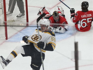 The Bruins' Tim Schaller celebrates with the Senators' Craig Anderson and Erik Karlsson on the ice after colliding.