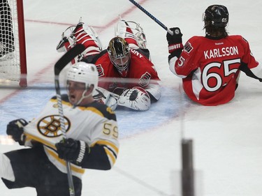 The Bruins' Tim Schaller celebrates with the Senators' Craig Anderson and Erik Karlsson on the ice after colliding.