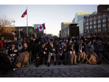 The setting sun shines on veterans before a candlelight gathering and light show at the National War Memorial to mark the 100th anniversary of the Battle of Vimy Ridge.