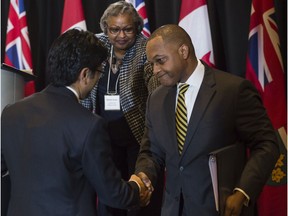 Justice Michael Tulloch shakes hands with Ontario Attorney General Yasir Naqvi after releasing his findings and recommendations on police oversight in the province of Ontario during a press conference in Toronto, Ontario, April 6, 2017.   (Tyler Anderson /  National Post)