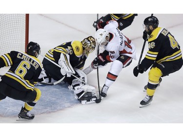 Boston Bruins goalie Tuukka Rask makes the save as the Ottawa Senators' Clarke MacArthur tries to poke the puck free during the first period.