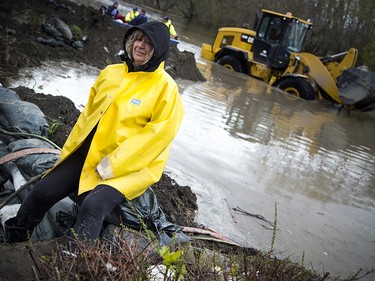 Jo-Anne Poulin sits on levee dike that is holding a flood of water back from her home and her neighbours. Poulin is incredibly thankful for a neighbour Claude Proulx who helped to build the dirt wall and the outpour of volunteers who have all come together to help protect her and the community. Flooding in the east end of Gatineau Sunday May 7, 2017.