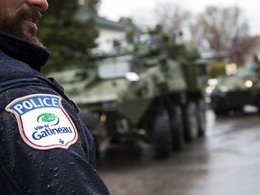 The Canadian Forces were called into Gatineau to help with the flooding in Gatineau Sunday May 7, 2017. A Gatineau Police officer stands along Rue Notre Dame as military vehicles pull in.
