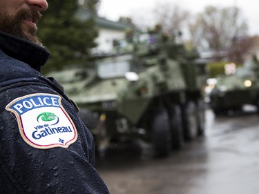 The Canadian Forces were called into Gatineau to help with the flooding in Gatineau Sunday May 7, 2017. A Gatineau Police officer stands along Rue Notre Dame as military vehicles pull in.