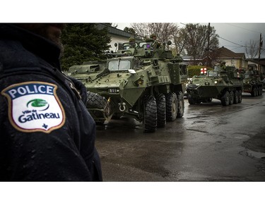 The Canadian Forces were called into Gatineau to help with the flooding in Gatineau Sunday May 7, 2017. A Gatineau Police officer stands along Rue Notre Dame as military vehicles pull in.