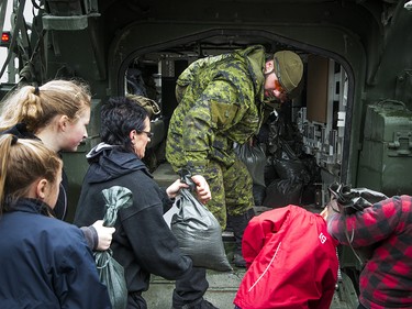 The Canadian Forces were called into Gatineau to help with the flooding in Gatineau Sunday May 7, 2017. A CF member reaches out of a Light Armoured Vehicle to volunteers passing along sandbags Sunday afternoon.