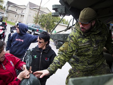 The Canadian Forces were called into Gatineau to help with the flooding in Gatineau Sunday May 7, 2017. A CF member reaches out of a Light Armoured Vehicle to volunteers passing along sandbags Sunday afternoon.