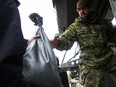 The Canadian Forces were called into Gatineau to help with the flooding in Gatineau Sunday May 7, 2017. A CF member reaches out of a Light Armoured Vehicle to volunteers passing along sandbags Sunday afternoon.