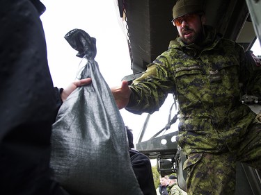 The Canadian Forces were called into Gatineau to help with the flooding in Gatineau Sunday May 7, 2017. A CF member reaches out of a Light Armoured Vehicle to volunteers passing along sandbags Sunday afternoon.