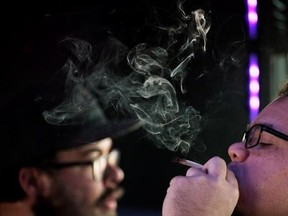 Phoenix Camacho, of Austin, Texas, right, smokes a marijuana cigarette as Scott Craft, of Aurora, Colo., looks out the window of a tour bus on Wednesday, April 26, 2017 throughout Denver. A group of ten tourists and Colorado residents traveled to a marijuana dispensary and a grow operation while consuming marijuana on the My 420 Tours vehicle.THE CANADIAN PRESS/Joe Mahoney