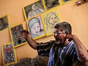 In this Sunday, April 30, 2017 photo, Iraqi painter Mustafa al-Taee sit in front of a display of his art work as he speaks to The Associated Press, at his home in the northern town of Hamam al-Alil, near Mosul, Iraq. After the Islamic State group swept into his town nearly three years ago, al-Taee resolved to bear witness to the militants‚Äô brutal rule by secretly painting what he had seen with his own eyes. The result was a gallery of horrors: car bombs, dead children, an IS defector beheaded