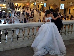 FILE - In this Aug. 8, 2014, file photo, a bride and groom lean over the east balcony as they pose for a photograph in Grand Central Terminal in New York. If you‚Äôre busy planning a wedding, you might want to consider insuring it. Wedding insurance policies are relatively easy to understand, and the two main types, liability and cancellation, are both inexpensive compared with the cost of a ceremony and reception. (AP Photo/Donald King, File)