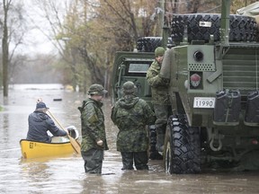 MONTREAL, QUE.: MAY 7, 2017 -- A man in a canoe paddles by Canadian military personnel next to their TAPV, on the flooded avenue du Chateaux-Pierrefonds in Montreal on Sunday May 7, 2017. (Pierre Obendrauf / MONTREAL GAZETTE) ORG XMIT: 58567 - 6435