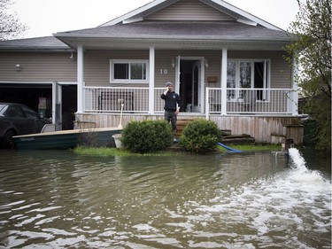 A man stands in the yard of a home on Rue Adelard where heavy flooding has hit in the Gatineau area Sunday May 7, 2017.