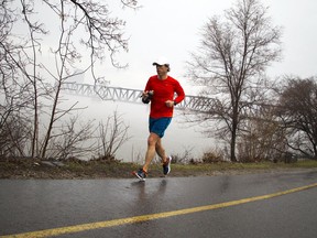 A runner passes the Prince of Wales Bridge along the Ottawa River as the river was blanketed with fog Sunday April 16, 2017.   Ashley Fraser/Postmedia