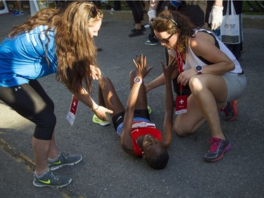 A woman gets help after falling to the ground after crossing the 10K finish line.
