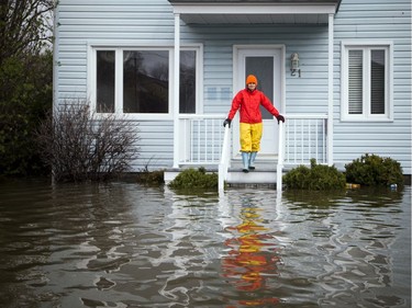 A woman stands on the step of a home at the corner of Rue Blais and Rue Adelard where the heavy flooding has hit in the Gatineau area Sunday May 7, 2017.