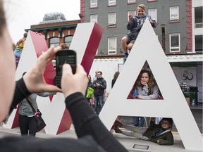 Barbara Curran, left, takes a picture of, from top right, Vuk Stojnic, Casia Stojnic and Javor Stojnic, as they pose in the "A" of the OTTAWA sign inside Inspiration Village in the Byward Market Monday, May 22, 2017. (Photo/Darren Brown)