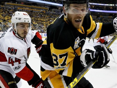 The Pittsburgh Penguins' Carter Rowney and the Ottawa Senators' Jean-Gabriel Pageau battle along the boards.