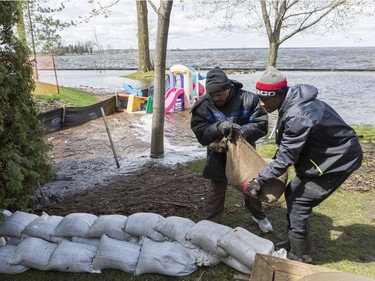 Courtney Roberts (L) and Bryson Patterson-Blasse help to place sandbags to protect a family friends house from flooding in Britannia Village in Ottawa. May 3,2017.