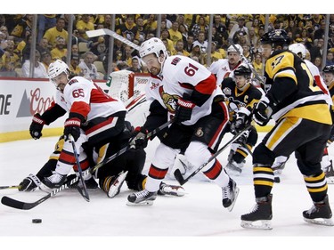 The Ottawa Senators' Mark Stone and Erik Karlsson (65) try to clear the puck.