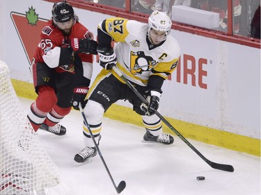 Ottawa Senators defenceman Erik Karlsson (65) and Pittsburgh Penguins centre Sidney Crosby (87) battle for control of the puck behind the net during the first period of game three of the Eastern Conference final in the NHL Stanley Cup hockey playoffs in Ottawa on Wednesday, May 17, 2017.