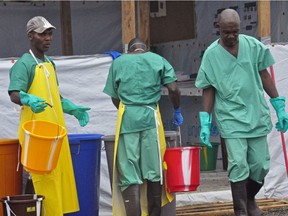 In this Monday, Aug .18, 2014 file photo, health workers with buckets, as part of their Ebola virus prevention protective gear, work at an Ebola treatment centre in Monrovia, Liberia. Ebola is back in Africa, the WHO announced last week.