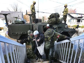 Cpl. Nicolas Lanctot and Cpl. Jean-Robert Isabelle help Louise David back to her home Rue René in Gatineau Friday May 12, 2017. It was the first time Louise has been home since the flooding began.   Tony Caldwell
