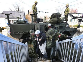Cpl. Nicolas Lanctot and Cpl. Jean-Robert Isabelle help Louise David back to her home on Rue René in Gatineau Friday, the first time she's been home since the flooding began.