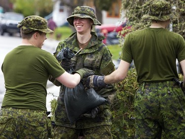Soldiers form a line to help residents on rue Watt in Gatineau pick up sandbags that are no longer needed.