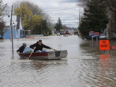Gatineau emergency workers and neighbours helped the people of Rue Saint-Louis in Gatineau Wednesday May 3, 2017. More rain has caused water to rise and flooded more people out of their homes. Rene Puccini (right) takes his pet bird to safety by boat Wednesday.