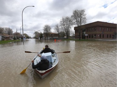 Gatineau emergency workers and neighbours helped the people of Rue Saint-Louis in Gatineau Wednesday May 3, 2017. More rain has caused water to rise and flooded more people out of their homes. Rene Puccini (back) takes his pet bird to safety by boat Wednesday.