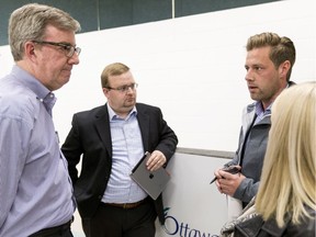 Ottawa Mayor Jim Watson, left, and Cumberland Ward Coun. Stephen Blais talk with André Morin and his partner Amanda Joanis, who own a house on Petrie Island, following a disaster recovery information session at the R.J. Kennedy Community Hall.