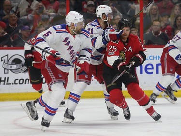 The Senators' Chris Neil tries to fight his way througha couple of Rangers.
