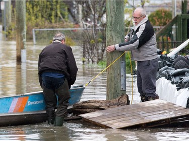 Residents tie up a boat on Rue Moreau in Gatineau as flooding continues throughout the region in areas along the local rivers.
