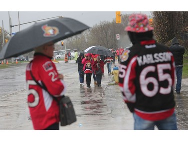 Ottawa Senators fans take cover under umbrellas as they arrive at the Canadian Tire Centre on Saturday.
