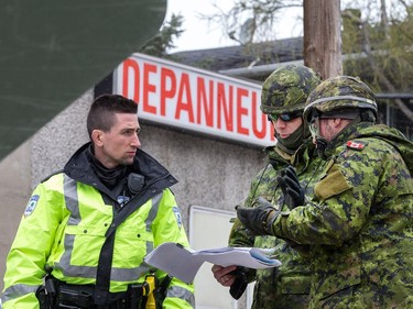 Soldiers check for directions from a Gatineau police officer on Rue Glaude in Gatineau as flooding continues throughout the region in areas along the local rivers.
