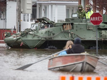 Soldiers in an armoured vehicle drive past a row boat on Rue Glaude in Gatineau as flooding continues throughout the region in areas along the local rivers.