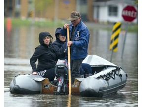 Stephanie Charron and Lorraine Girard get a ride out to check the status of Girard's home on Rue Adelard on Saturday. Ashley Fraser/Postmedia