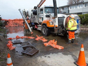 Workers clear a plugged drain on Jamieson St beside Britannia Bay as flooding continues throughout the region in areas along the local rivers.